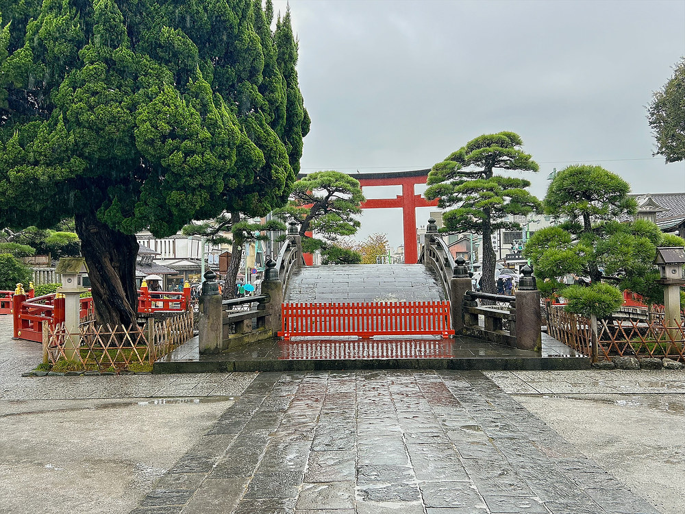 Stone path, arched bridge and red torii on the approach to Tsurugaoka Hachimangu on a rainy day
